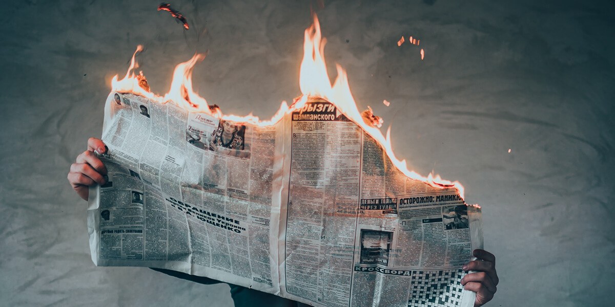 Photo of illustration of person sitting and reading a burning newspaper